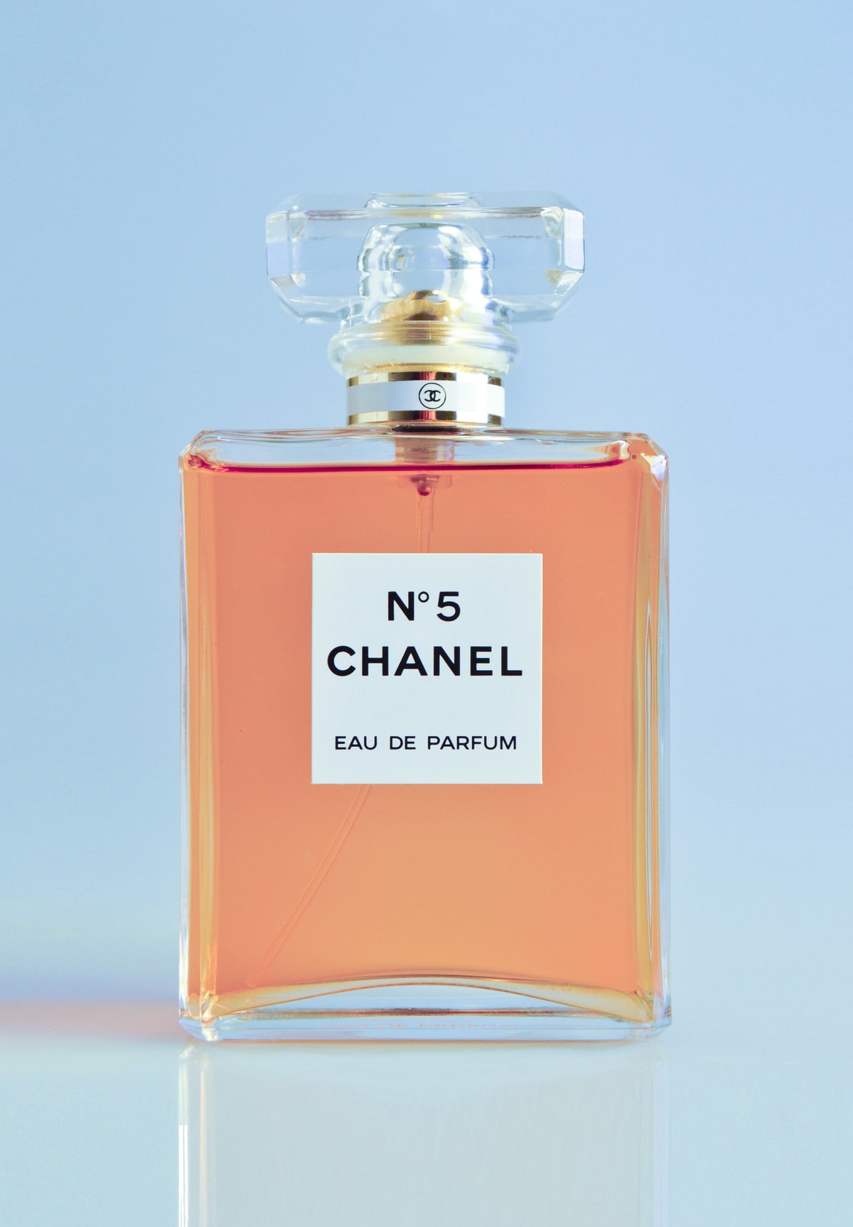 Original studio photograph of an amber perfume bottle against a pale blue background