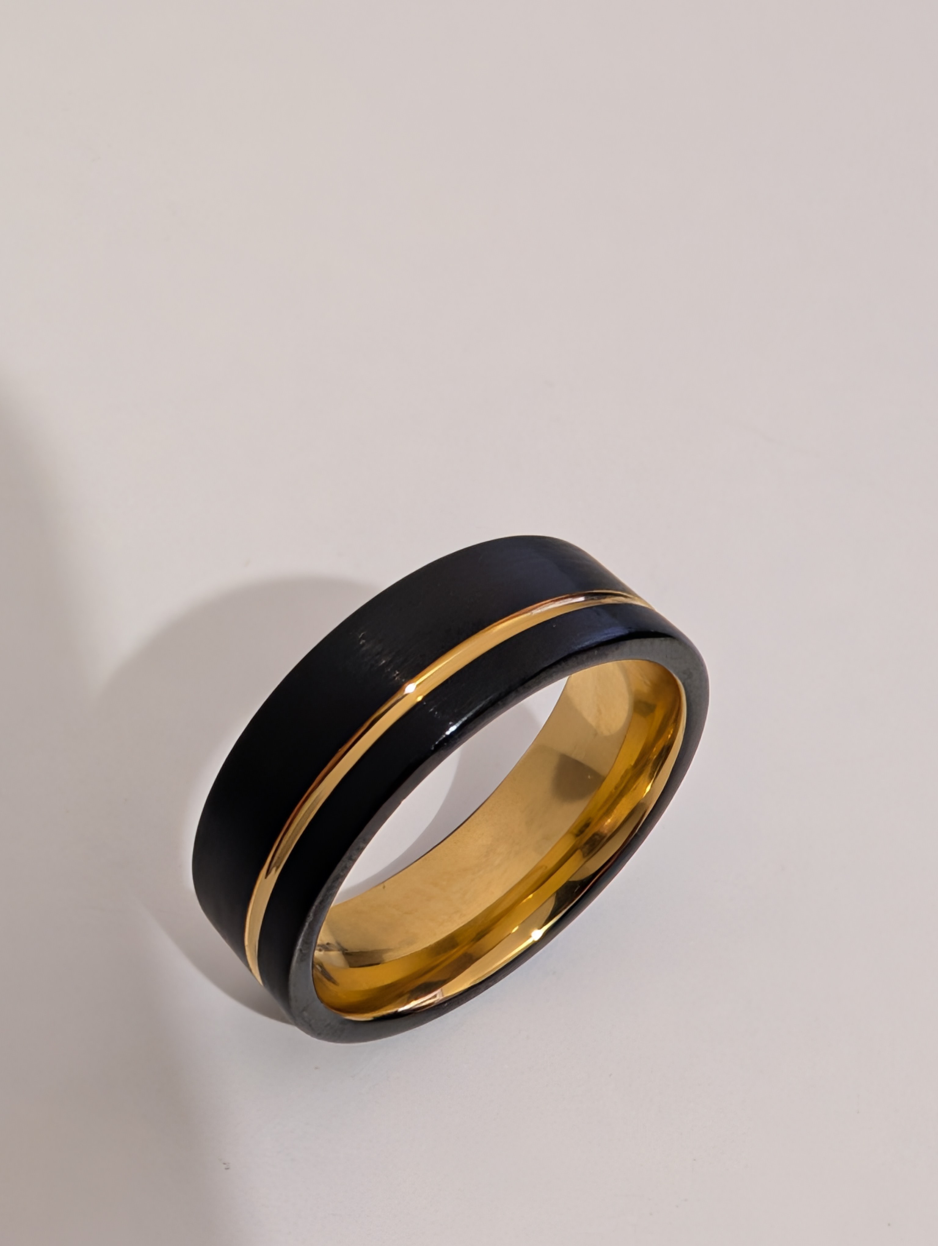 Original product photograph of a black and gold ring